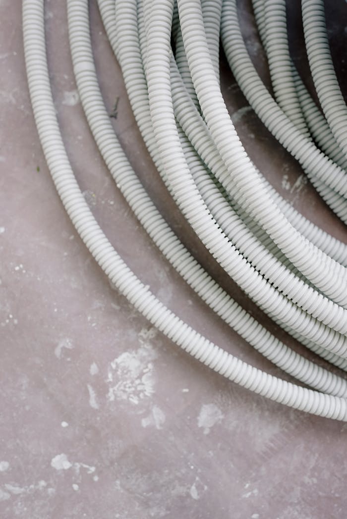 Close-up of coiled white electrical wire on a rough, textured concrete surface.